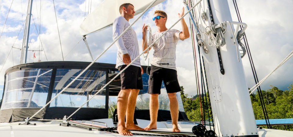 Crew member teaching an Apprentice about hoisting sails onboard a luxury yacht