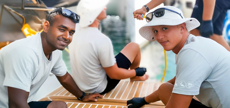 Deck crew diligently cleaning a teak deck on a yacht