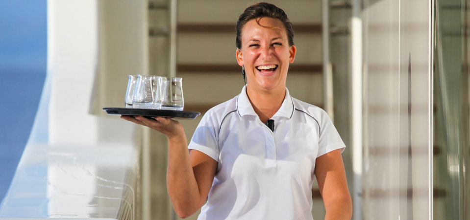 Stewardess serving drinks to guests onboard a luxury superyacht