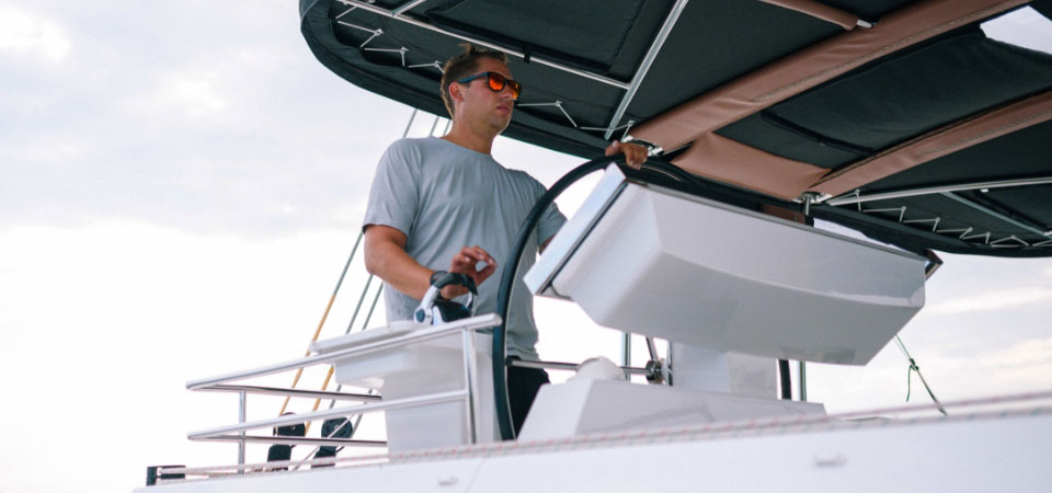 Yacht crew member sailing a small luxury catamaran